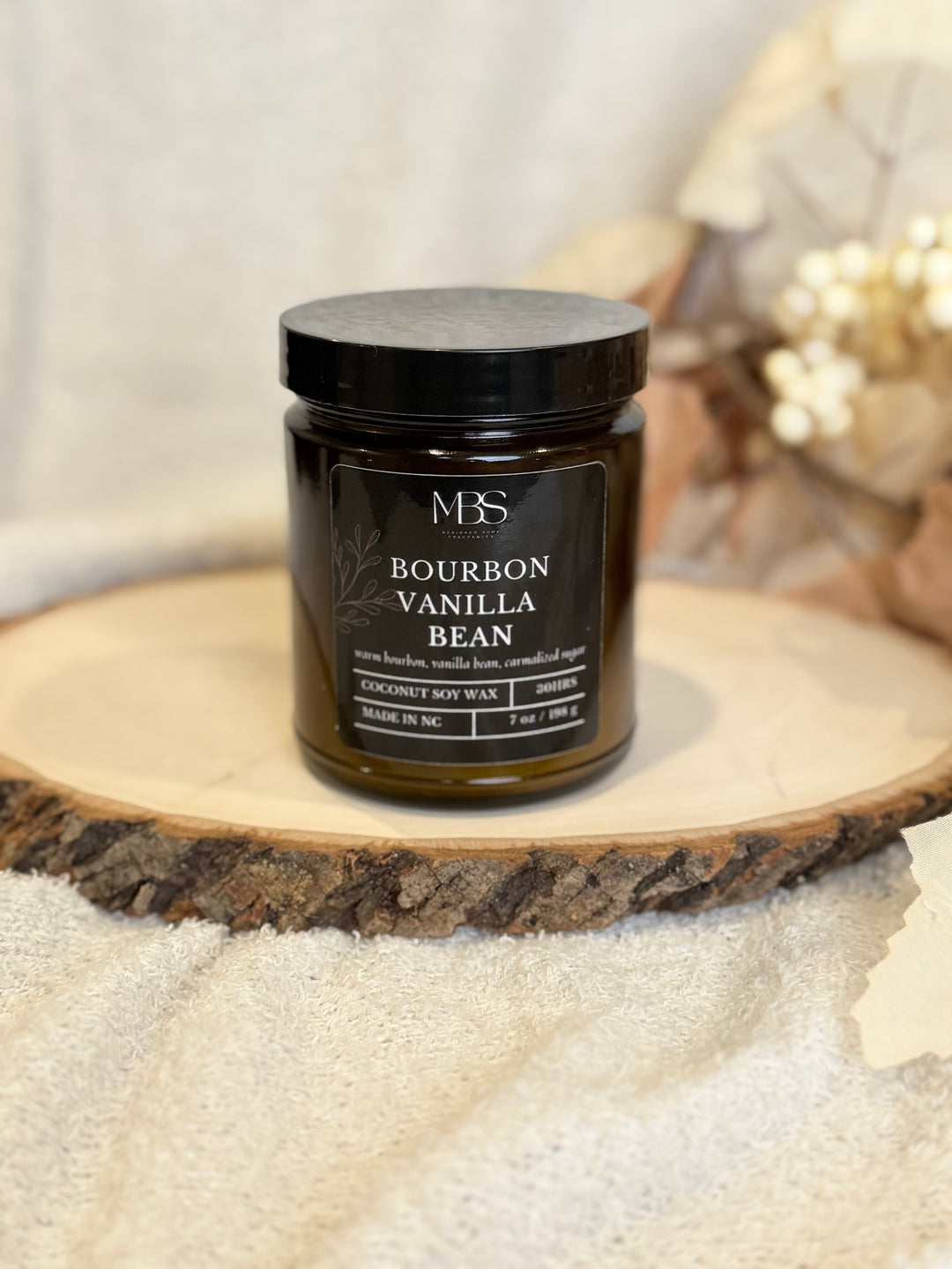 Jar of bourbon vanilla bean candle on a wooden surface with a blurred background