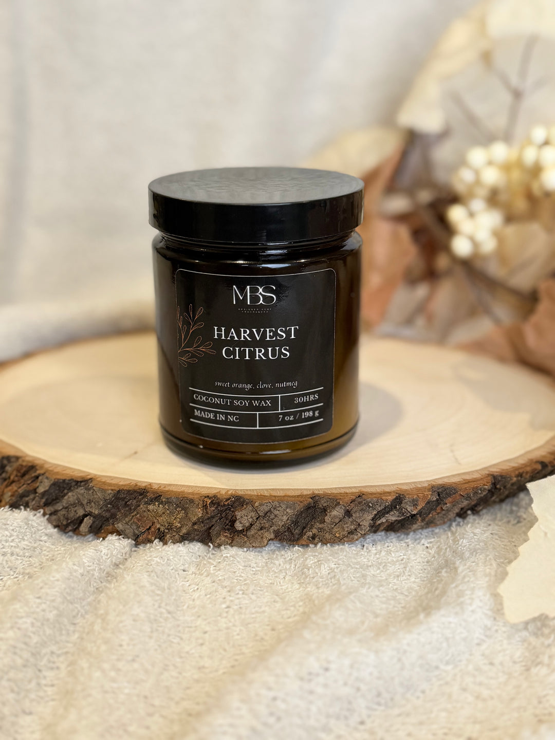 Jar of 'Harvest Citrus' candle on a wooden surface with a blurred background